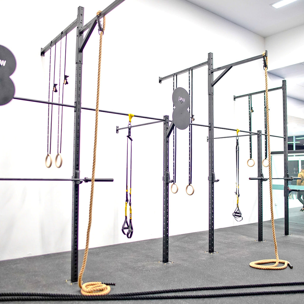Gym setup with pull-up bars and ropes on a white wall background